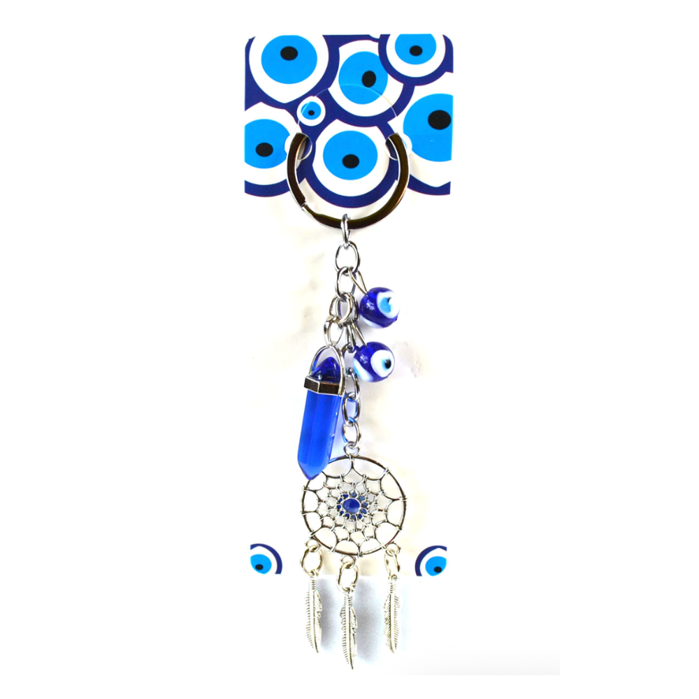A blue and white evil eye themed keychain or bag charm featuring a silver-tone metal ring, evil eye beads, a blue crystal, a dreamcatcher, and dangling feather charms, attached to a matching patterned card.