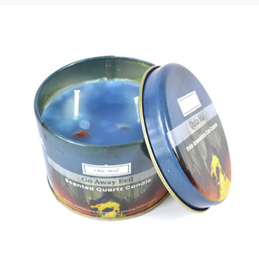 A scented wax candle in a round metal tin with the lid leaning against the front. The visible wax is blue, and the label reads 'Go Away Evil Scented Wax Candle' with a dark scenic-style print.