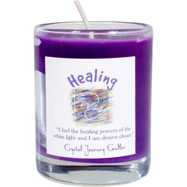 A purple votive candle with a label that reads 'Healing' and includes an inspirational message. The candle is set in a clear glass holder.